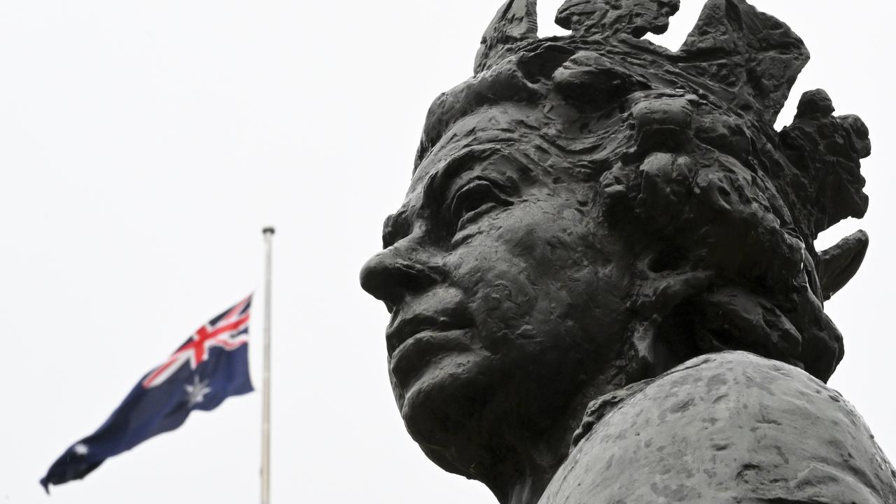 The Australian flag on a semi-pole behind the statue of Her Majesty the Queen at Parliament House in Canberra, Australia