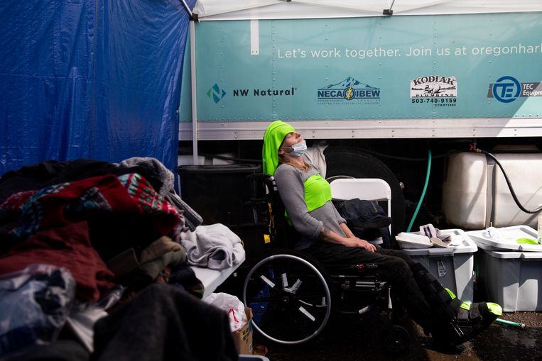 A woman in a cooling center wears cold clothes on her head and chest.  Washington Post image