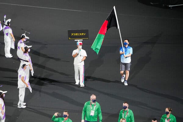 A volunteer carrying the flag of Afghanistan in the place of the absent athletes,