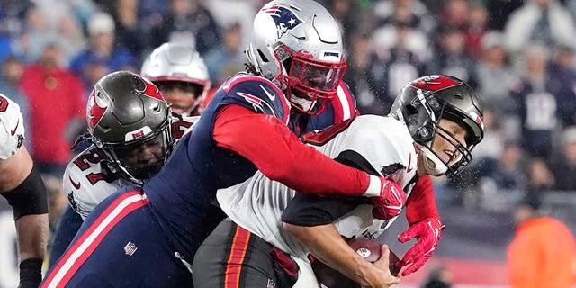 Tampa Bay Buccaneers quarterback Tom Brady, right, is sacked by New England Patriots outside linebacker Matt Godon, left, during the first half of an NFL football game, Sunday, October 3, 2021, in Foxboro, Massachusetts.