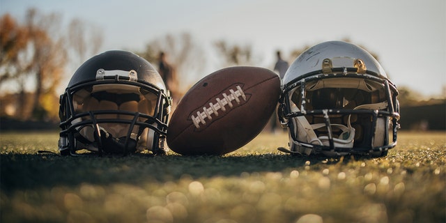 American football helmets and the ball in the field, no people.