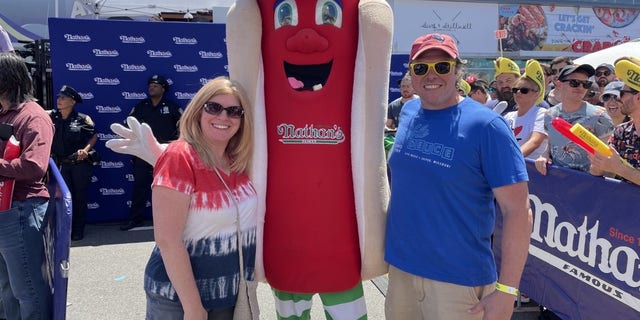 Valerie Solemini and Frankie Capobianco, both from Boston, join thousands of sunny revelers during Nathan's famous hot dog eating competition in Coney Island, New York, on July 4, 2022.