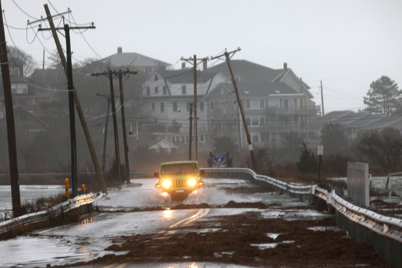A driver makes their way through a flooded street at high tide during a winter storm in Gloucester