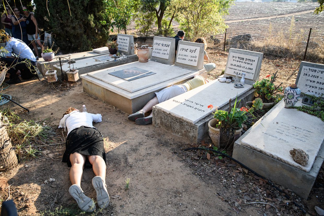 Visitors to Tom Godeau's funeral take shelter from Hamas rockets among the graves after air raid sirens sound.  Photo by Matan Golan for Volkskrant