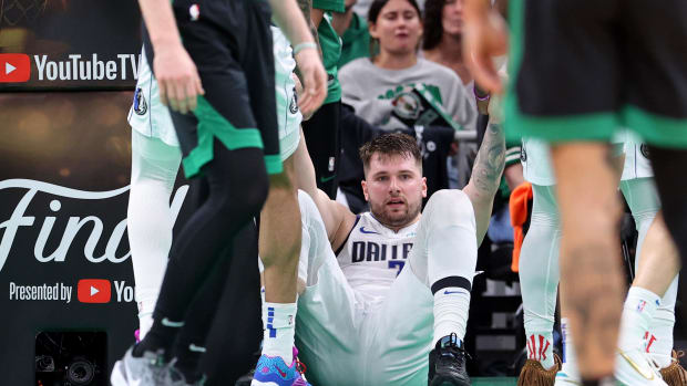 June 9, 2024;  Boston, Massachusetts, USA;  Dallas Mavericks guard Luka Doncic (77) is assisted after making a play against the Boston Celtics during the third quarter of Game 2 of the 2024 NBA Finals at TD Garden.  Mandatory Credit: Peter Casey-USA TODAY Sports